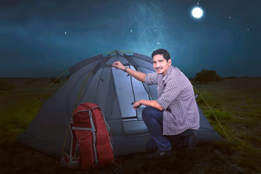 Young asian traveler man set up the tent for his rest at night