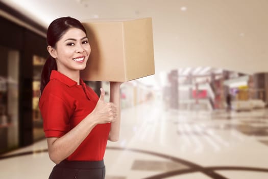 Smiling asian courier woman carrying the parcel to deliver