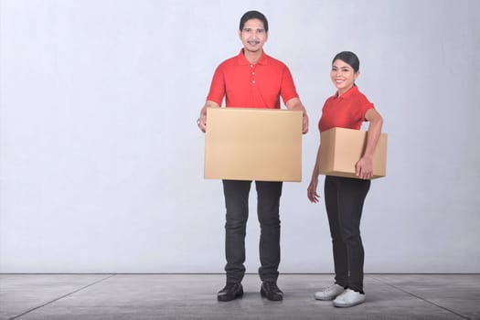 Attractive asian delivery service team with cardboards box over wall background