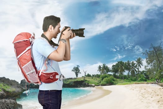 Attractive asian photographer man taking a photos on the beach