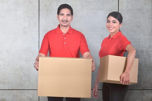 Young asian delivery service team with the parcel standing over wall background