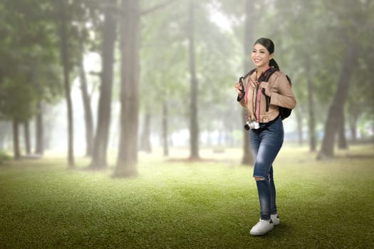 Pretty asian tourist woman with backpack and camera walking on the forest