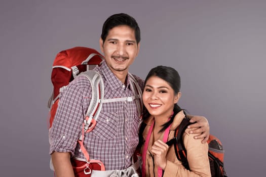 Young asian traveler couple with backpack over colored background