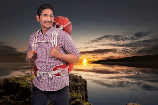 Young asian backpacker man enjoying sunset view from the top