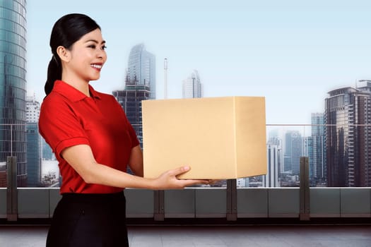 Young asian delivery woman carrying the package on the modern building