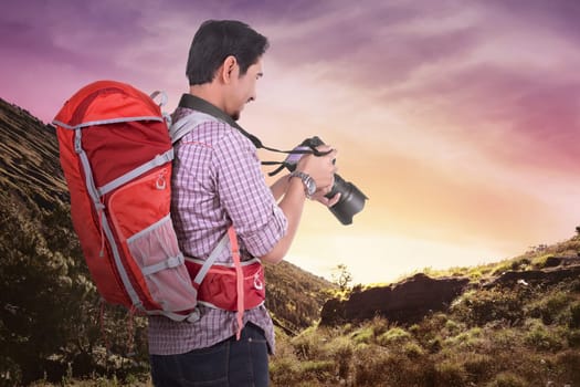 Happy asian photographer with his camera on the mountain