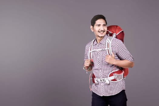 Happy asian backpacker ready to make a trip over colored background