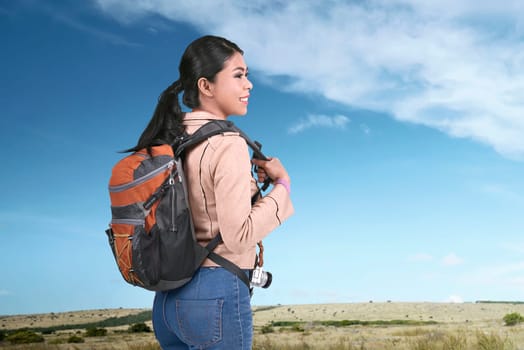 Smiling asian traveler carrying backpack at journey on the field