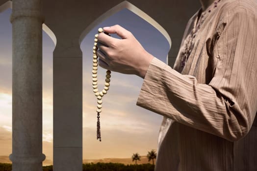 Muslim man praying with prayer beads on the mosque