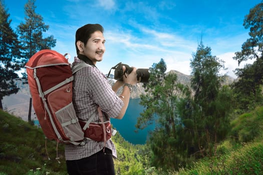 Happy asian traveler man with camera and backpack with scenery background