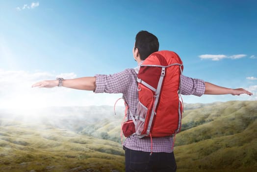 Young asian backpacker enjoying the landscape with blue sky background