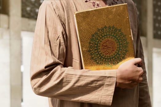 Muslim man holding Quran in the mosque