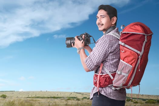 Smiling asian tourist with backpack and camera at outdoor