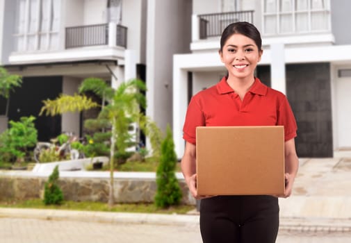Young asian courier woman delivering package in front of house of packet receiver