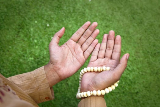 Muslim man praying with prayer beads at outdoor