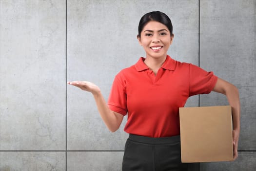 Smiling asian delivery woman with parcel over gray wall background