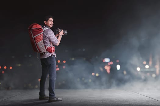 Handsome asian traveler with backpack and camera against blur light background