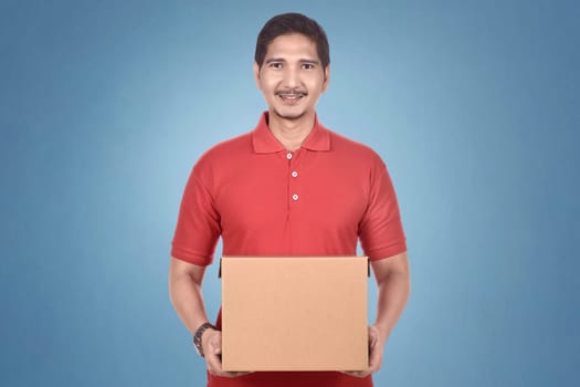 Attractive asian courier man holding package over bright background