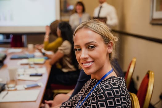 Young businesswoman turning around in a conference meeting to get a headshot taken.