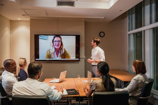 Group of business people having a late night video conference meeting. Sitting around a conference table talking and networking.