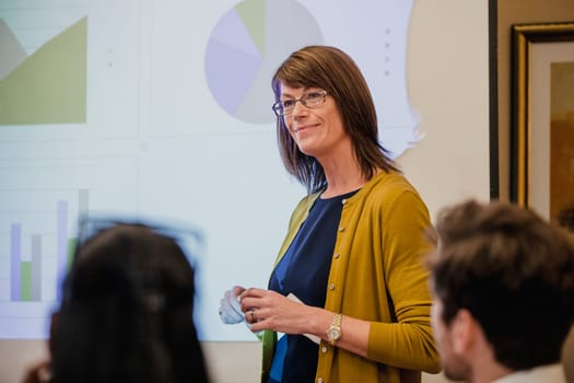 Rear view, close-up of business people listening to a presenter at a presentation. The presenter is listening to what the business people have to say.