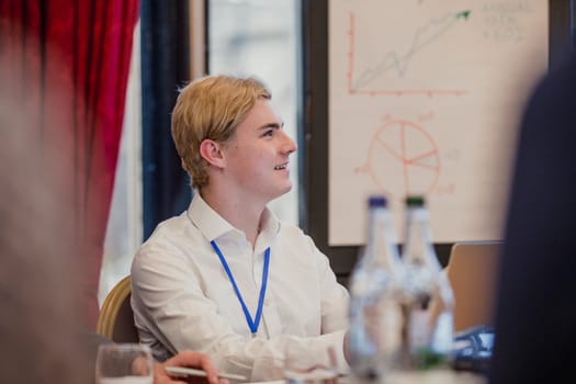 Close-up, side view of a young businessman sitting at a table in a business meeting.