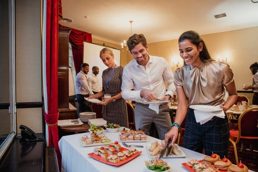 Front view of business people getting food from a buffet at a conference meeting.
