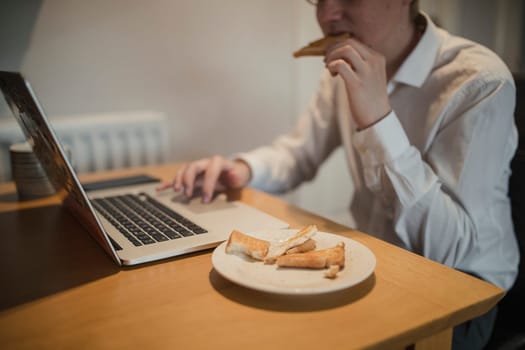 Young male adult checking emails while eating breakfast on a morning.