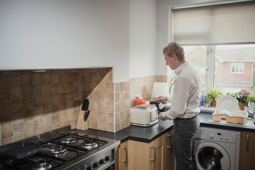 Wide angle, rear view of a young adult businessman making some toast for breakfast before work.