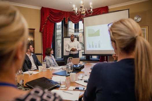 Rear view of a group of business people listening to a businessman giving a financial presentation.