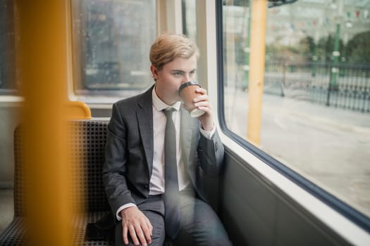 Businessman sitting on a train with a coffe on his morning commute to work.