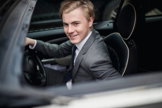 High angle view of a businessman through a car sun roof while sitting and waiting to drive to work.