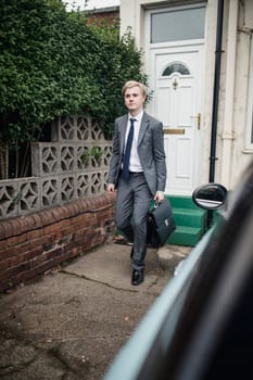 Young businessman walking out the house to go tot the car to commute to work.