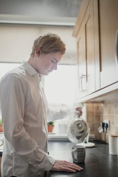 Young male adult making a cup of tea. Having regular cup of tea before work.