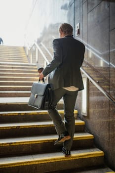 Rear view of a young businessman walking up the stairs in the trian station on his morning commute.
