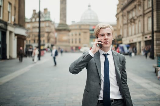 Businessman walking through the streets of the city to get to his business meeting. Making a phone call on route to work.