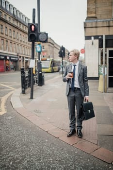 Front view of a young businessman waiting at the traffic lights to cross the road.