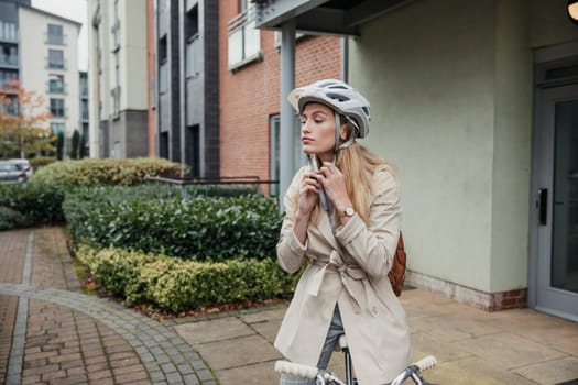 Front view of a young female adult fastening her helmet before cycling into work.