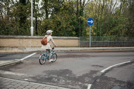 Wide angle, rear view of an unrecognisable person using a bike as her mode of transport to get to work.