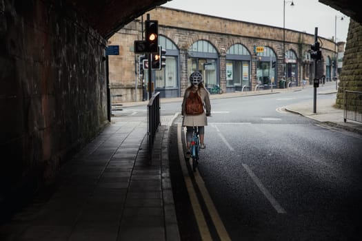 Rear view of a unrecognisable person cycling under a bridge to get to work.