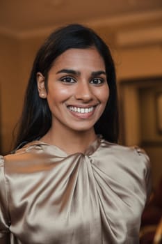 Close-up, front view portrait of a young businesswoman smiling for the camera.