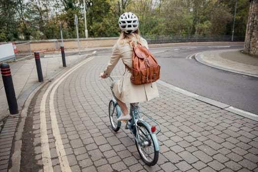 Rear view of an unrecognisable person cycling down the street on the way to work.