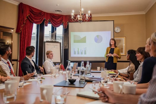 Surface level view of a business woman giving a presentation in a meeting.