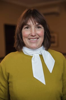 Close-up, front view portrait of a mature businesswoman smiling for the camera.