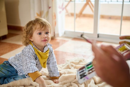 A young child enthusiastically interacts with an adult indoors, suggesting a playful and engaging family moment filled with joy.