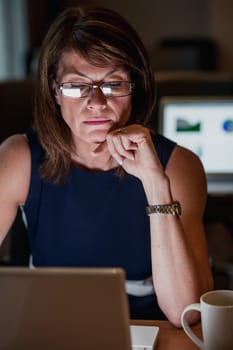 Mature Businesswoman working late in the office to get her work finished for the deadline.