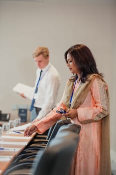 Businessman and Businesswoman setting up the conference room for a meeting, laying pens and paper out for notes.