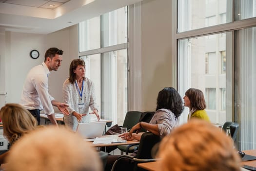 Businessman and woman talking to other their colleagues after giving a presentation within a meeting.