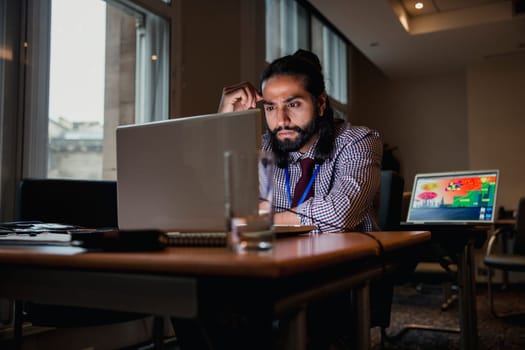 Young Businessman sitting alone in a board room working after hours to get more work done.
