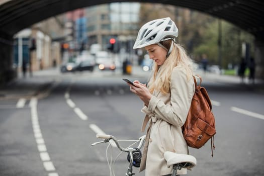 Young businesswoman checking the notifications on her mobile phone while cycling to work.